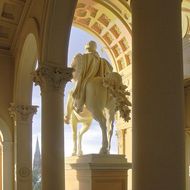 Blick über die Stadt und auf die Reiterstatue durch die Säulen im Baustil der Neorenaissance des Residenzschlosses.